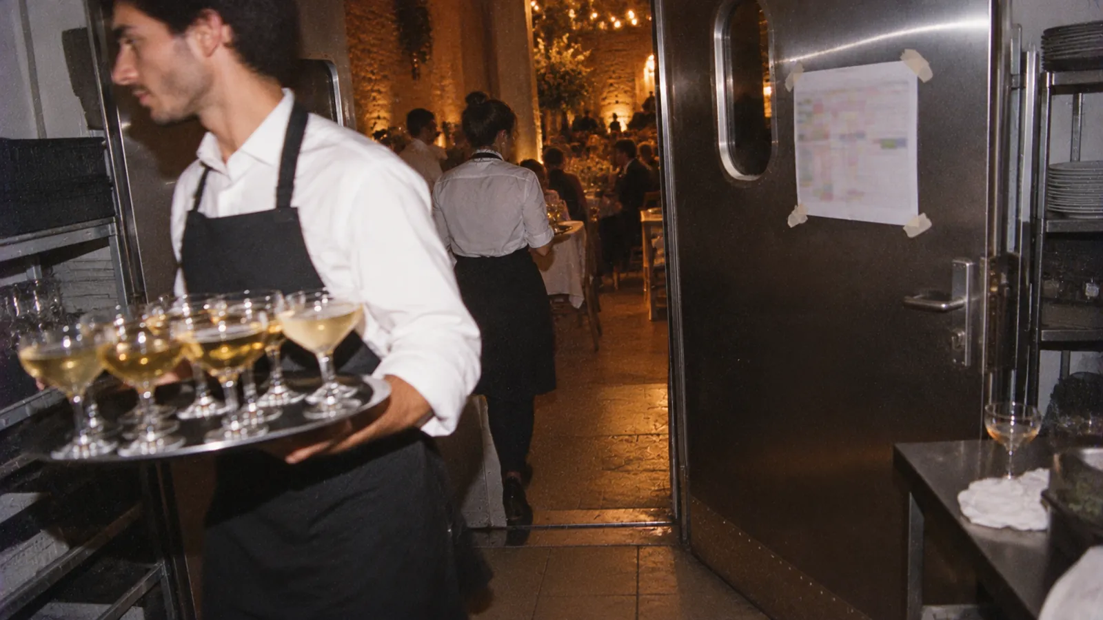 A wedding-day schedule taped to a kitchen door, lit by a camera flash during a wedding