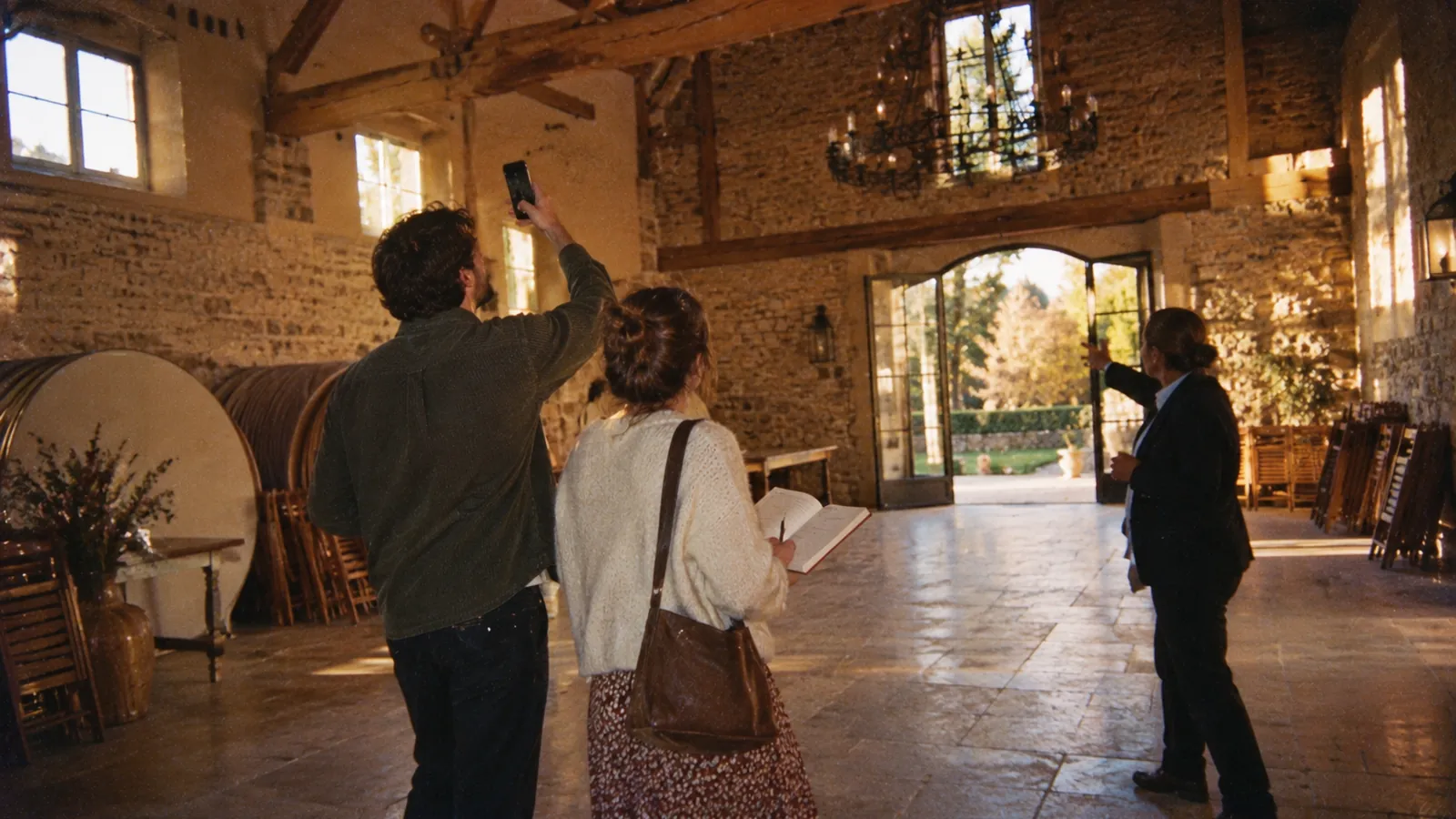A couple visiting an empty reception hall, notebook in hand
